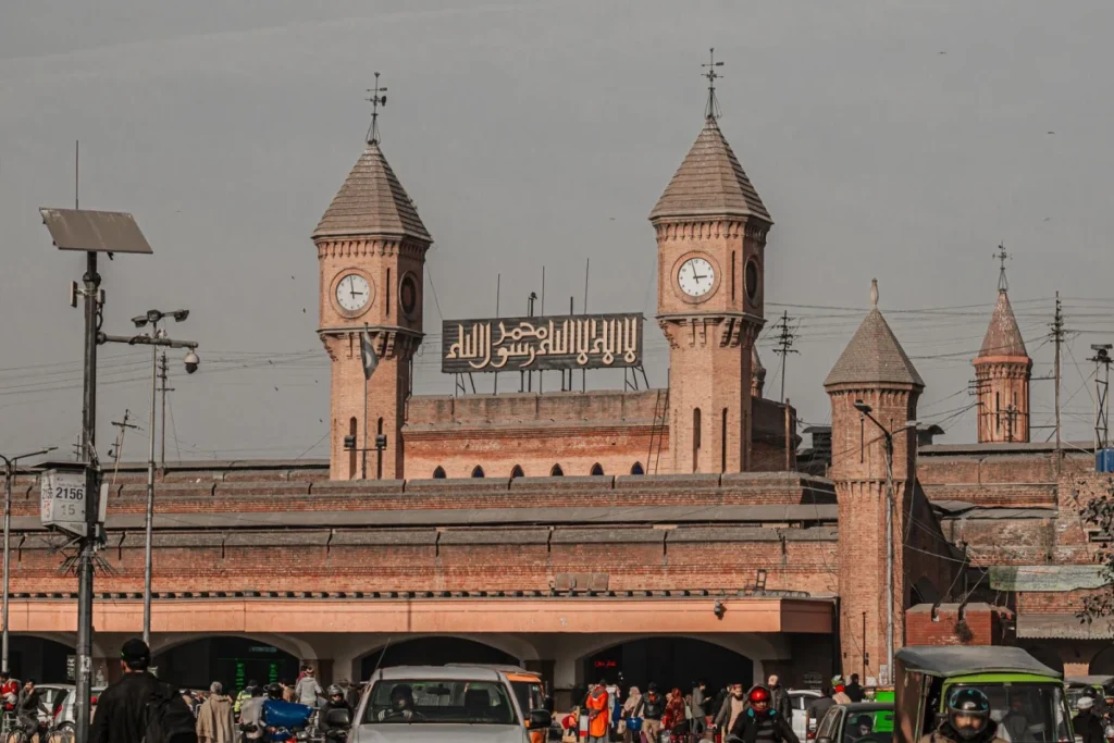 Historic clock-tower facade outside Lahore Railway Station with street traffic.