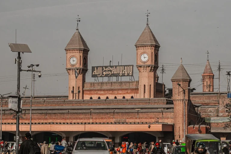 Historic clock-tower facade outside Lahore Railway Station with street traffic.
