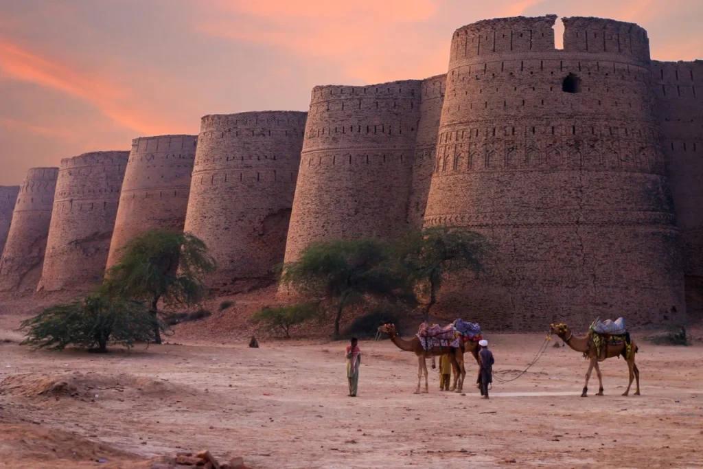 Derawar Fort's brick bastions at sunset with camels on the desert foreground in Punjab, Pakistan.