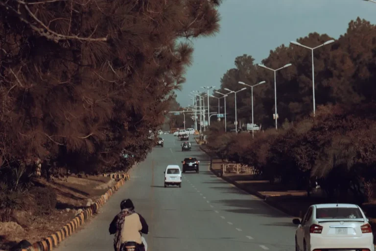 Tree-lined road with light traffic in Islamabad, Pakistan.