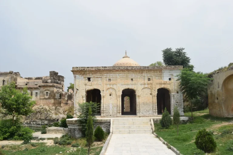 A historic stone pavilion with arched openings at the Katas Raj Temples complex in Pakistan's Salt Range.